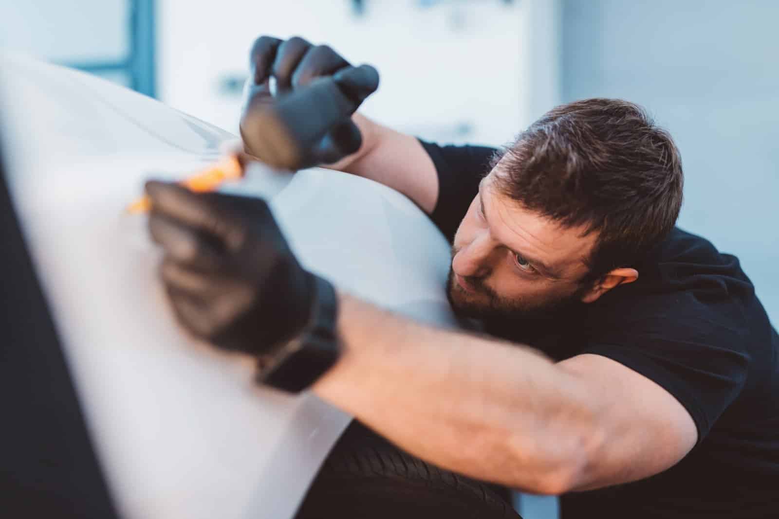 Car mechanic working to remove dent in workshop
